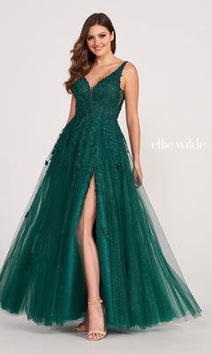 A woman poses against a plain background in the Ellie Wilde Side-Slit Long Prom Ball Gown EW34103—a sleeveless dark green lace gown with a deep V-neckline, floral appliqué, and high slit.