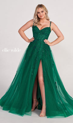 A woman poses against a plain background in the Ellie Wilde Long Glitter-Tulle A-Line Formal Dress featuring a sparkly emerald green fabric, sweetheart neckline, spaghetti straps, and a high slit.