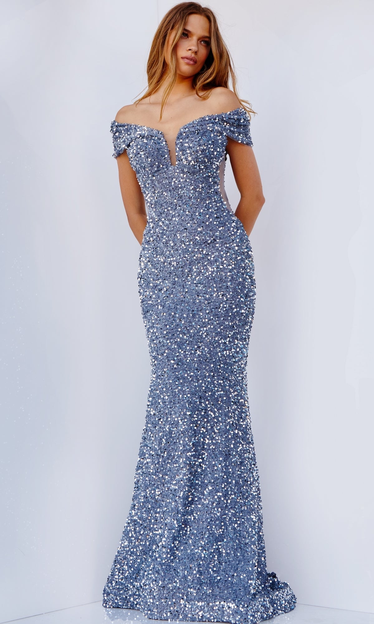A woman models the Jovani Sequin Off-the-Shoulder Prom Dress, a stunning fitted gown adorned with blue sequins—perfect for any special occasion.