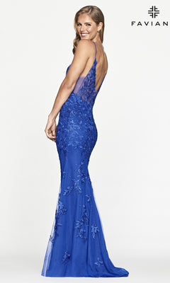 Woman in a sleeveless, floor-length blue Sheer-Sides Long Lace Prom Dress by Faviana with floral lace and a subtle deep V-neck poses sideways against a plain background; "FAVIAN" logo appears in the top right corner.