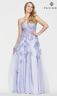 A woman smiles with one hand on her hip, wearing the Faviana Embroidered A-Line Long Prom Dress in lavender. The gown has 3-D embroidered flowers, a sheer overlay, thin straps, and a deep V neckline.