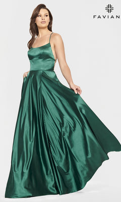A woman models the Long Open-Back Formal Prom Dress by Faviana—an emerald green, sleeveless satin gown—posed against a plain white background with the Faviana logo in the top right corner.