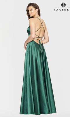A woman models the Long Open-Back Formal Prom Dress by Faviana in emerald green satin, featuring thin straps and a crisscross open back, standing against a white background. "FAVIAN" is displayed in the top right corner.