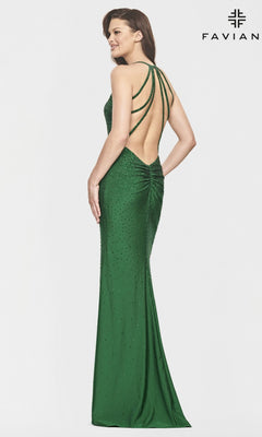 A woman models the Faviana Open-Back Beaded Long Prom Dress S10829 in emerald green, featuring multiple thin straps and beaded detailing, against a plain white background. The "FAVIANA" logo appears in the top right corner.