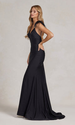 A woman stands in profile against a plain light background, modeling the Feather-Embellished Backless Long Prom Dress featuring feathered shoulder accents and a fitted silhouette.