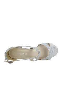 A top view of a single silver glitter high-heeled sandal with an ankle strap, open toe, and block heel. The insole reads "Touch Ups," making it the perfect choice for those seeking Aubrey Silver Prom Shoes by Touch Ups 4498.