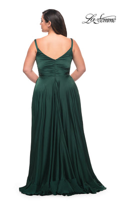 Woman wearing the Long Plus-Size La Femme Prom Dress featuring deep green satin, a floor-length sleeveless design, v-back, ruched bodice, and ruffle hem, standing against a white background.