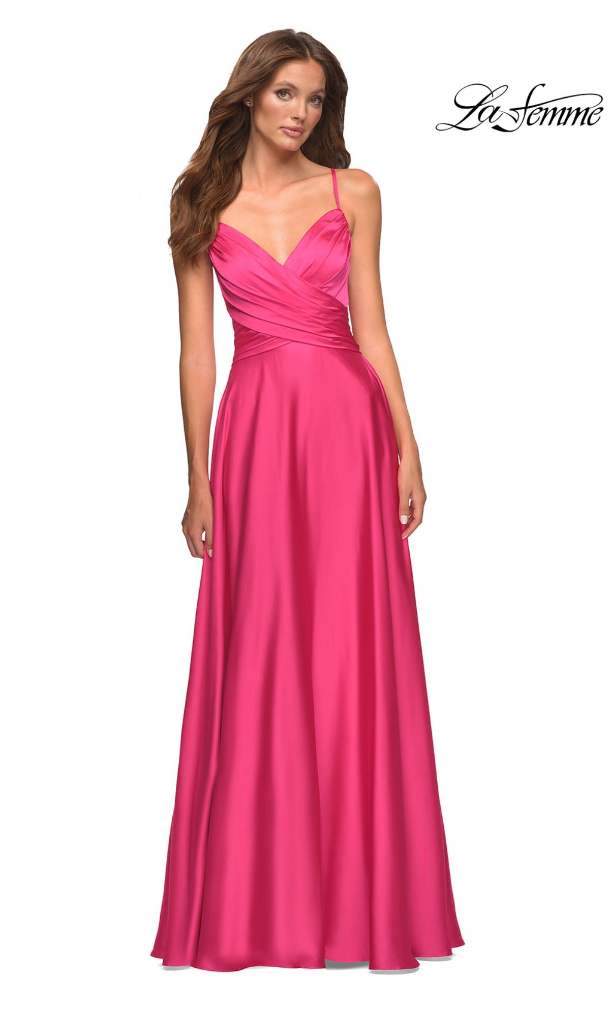 A woman wears the La Femme Backless Hot Pink Long Prom Dress, a floor-length A-line gown with a fitted bodice and flared skirt, standing against a white background with the La Femme logo in the top right corner.