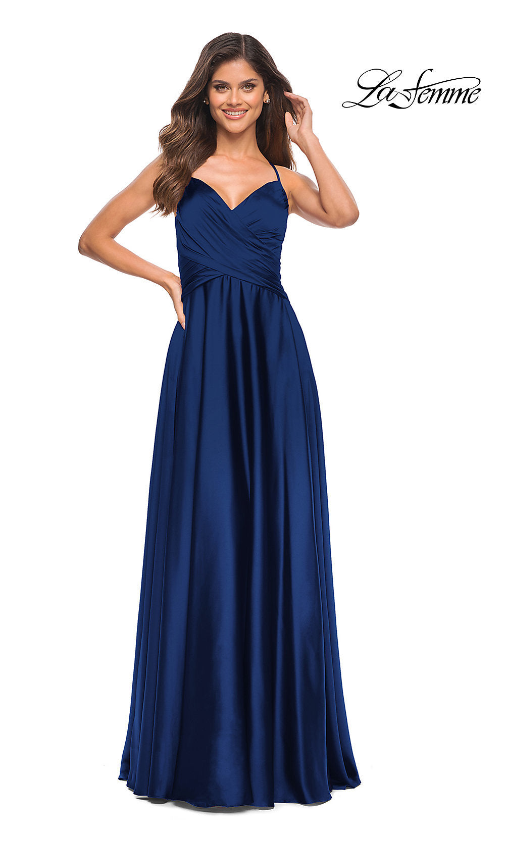 A woman stands smiling in a floor-length, sleeveless dark blue La Femme Lace-Up Back Long Satin A-Line Prom Dress with a sweetheart neckline.