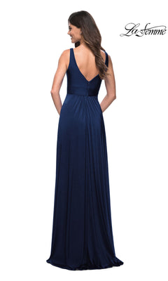 A woman stands facing away from the camera, modeling the La Femme Simple Long A-Line Formal Dress—a sleeveless, floor-length navy gown with a deep V-back. The "La Femme" logo appears in the top right corner.