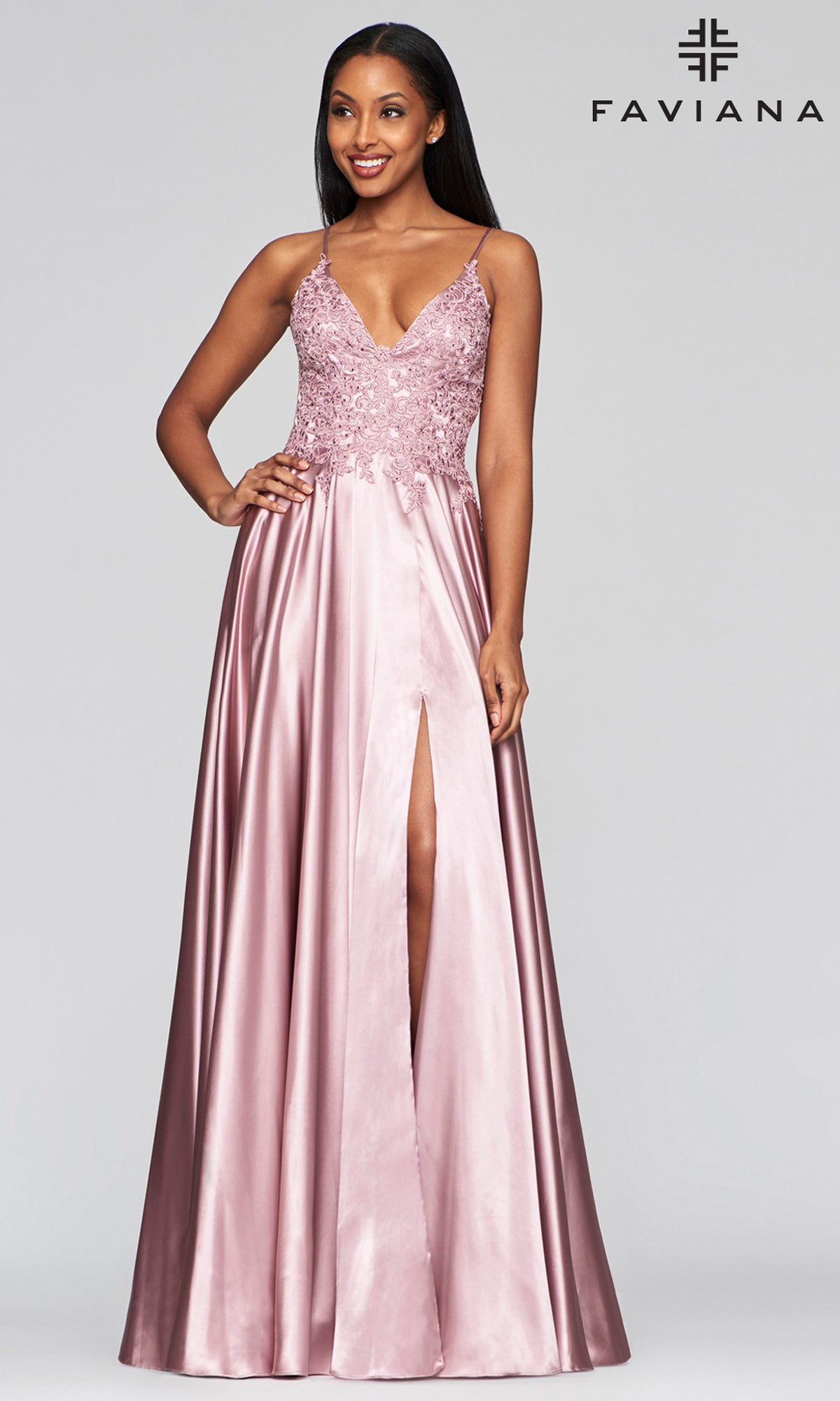 A woman models the Faviana Lace-Bodice Long A-Line Prom Dress—a sleeveless mauve satin gown with thin straps, embroidered lace bodice, and front leg slit—against a plain background. The Faviana logo appears in the top right corner.